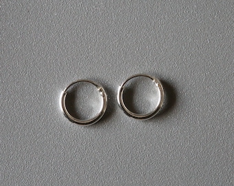 Puede incluir: Un par de pendientes de aro de plata. Los pendientes son simples y clásicos, y serían una gran adición a cualquier colección de joyas.