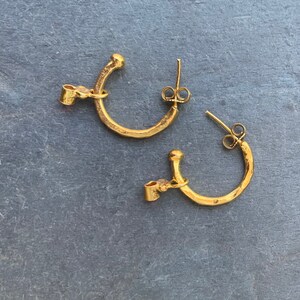 May include: A pair of gold hoop earrings with a hammered texture. The earrings have a simple, minimalist design.
