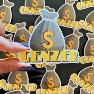 May include: A sticker with a cartoon money bag and the text "GENZEB" in yellow letters. The money bag is gray with a yellow dollar sign. The sticker is surrounded by other similar stickers.