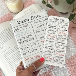 May include: Two white cards with black text listing dates and the words "Date Due:". The cards are held in a hand with a pink and white checkered background.