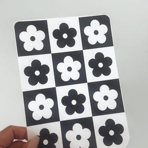 Könnte beinhalten: Ein schwarz-weiß karierter Aufkleber mit einem sich wiederholenden Muster aus stilisierten Blumen. Die Blumen sind schwarz auf weißem Hintergrund und weiß auf schwarzem Hintergrund.