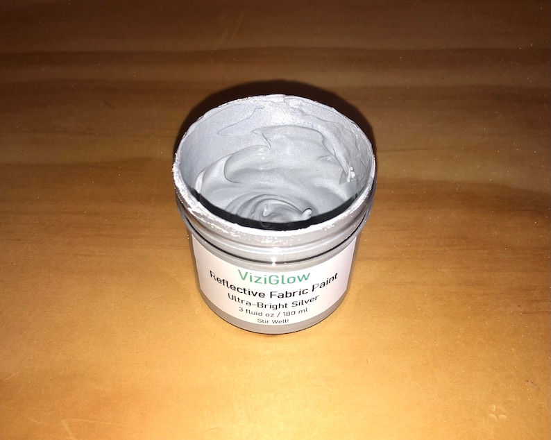 May include: A small jar of silver reflective fabric paint labeled "ViziGlow Reflective Fabric Paint Ultra-Bright Silver 3 fluid oz / 180 ml Stir Well."