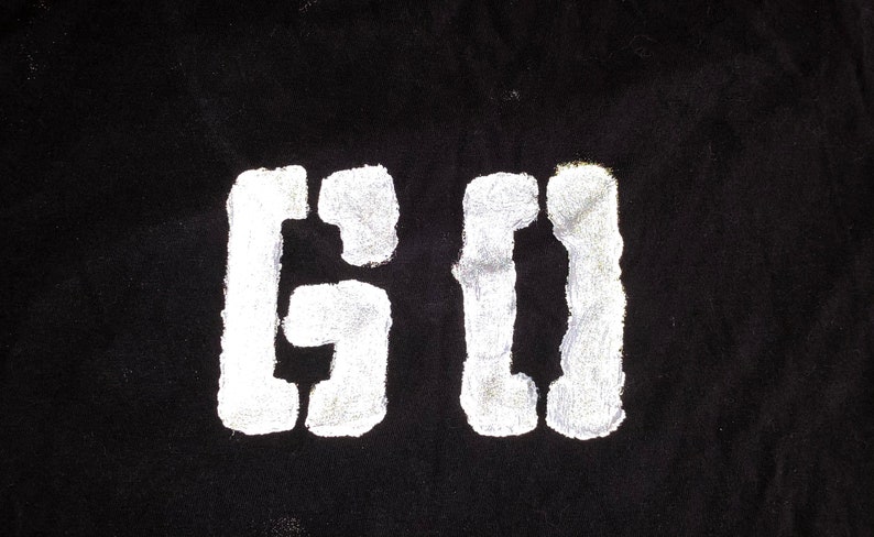 May include: White stencil letters "GO" on a black background.