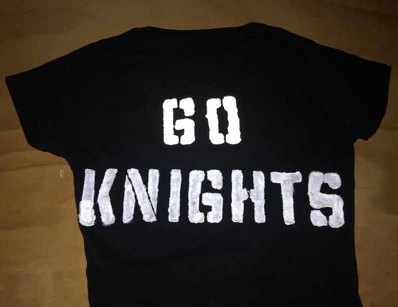 May include: Black t-shirt with white reflective paint, featuring the words "GO KNIGHTS" on the back.