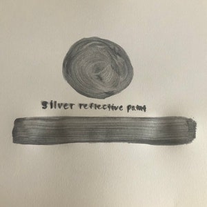 May include: A silver reflective paint swatch. The paint is shown in a circle and a long rectangle. The text "silver reflective paint" is written below the circle.