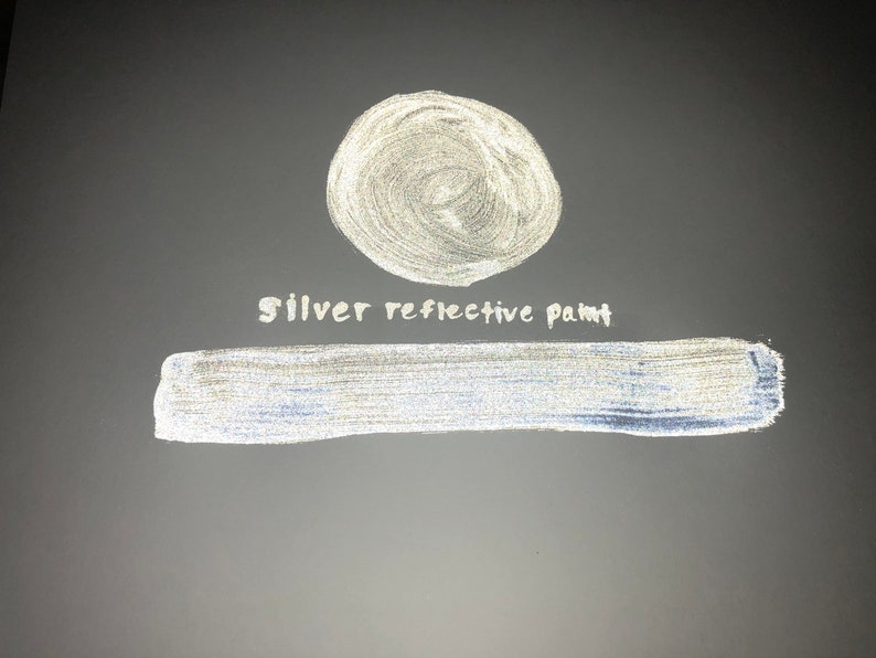 May include: A silver reflective paint sample. The paint is shown in a circle and a long rectangle. The text "Silver reflective paint" is written in white below the circle.