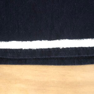 May include: Black t-shirt with a white stripe across the bottom.