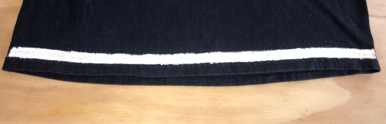 May include: Black t-shirt with a white stripe across the bottom.