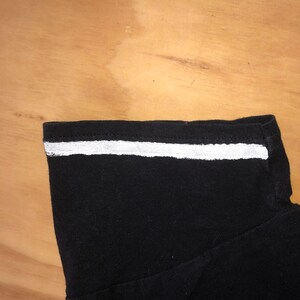 May include: Black shirt with a white stripe across the neckline.