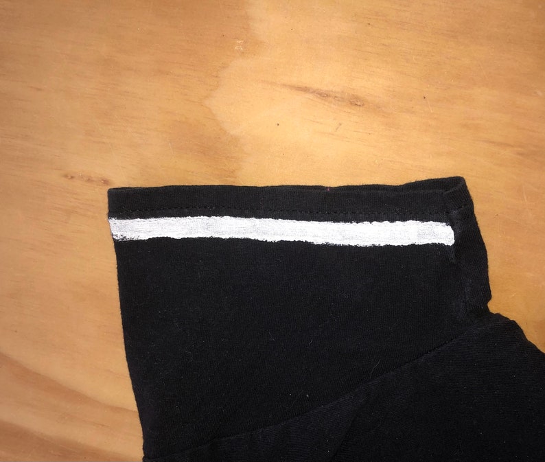 May include: Black shirt with a white stripe across the neckline.