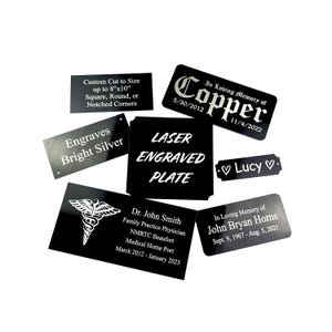 K&ouml;nnte beinhalten: Eine Sammlung von schwarz lasergravierten Platten mit wei&szlig;em Text. Einige Platten enthalten Texte wie "Custom Cut to Size", "Engraves Bright Silver" und "Laser Engraved Plate". Andere Platten enthalten Namen und Daten.