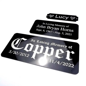 K&ouml;nnte beinhalten: Schwarze Gedenktafeln mit wei&szlig;em Text. Eine Tafel tr&auml;gt die Aufschrift "Lucy" mit Herzen. Eine andere lautet "In Loving Memory of John Bryan Horns" mit Daten. Die gr&ouml;&szlig;te Tafel tr&auml;gt die Aufschrift "In Loving Memory of Copper" mit Daten.