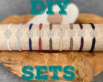 May include: DIY bracelet sets with silver charms in various colors, including white, navy, red, green, beige, brown, and black. The bracelets are displayed on a wooden surface.