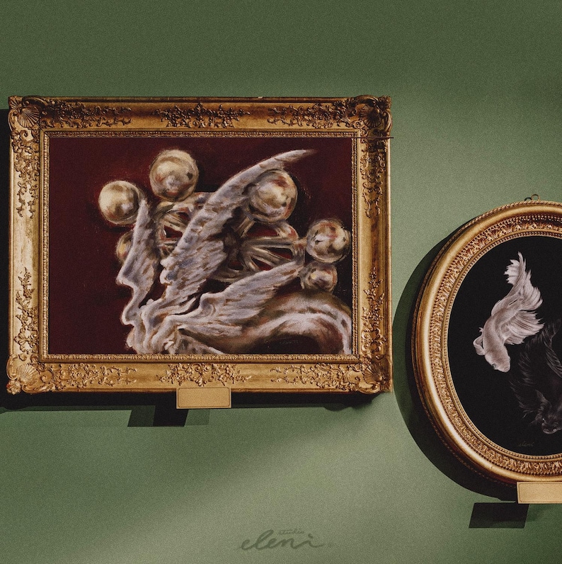 May include: A rectangular painting in an ornate gold frame featuring a dark red background with golden spheres and white, wing-like forms. Beside it, a smaller oval painting in a gold frame depicts a white fish against a black background.