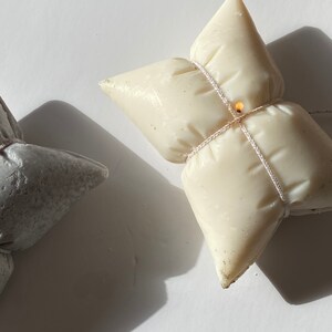 May include: Two handmade candles shaped like butterflies. One candle is white and the other is grey.
