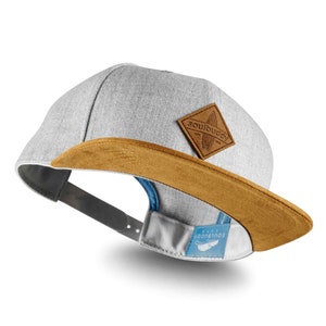 Seitliche Ansicht der Snapback Cap in Dunkelgrau. Der dunkelgraue Schirm ist gut sichtbar.