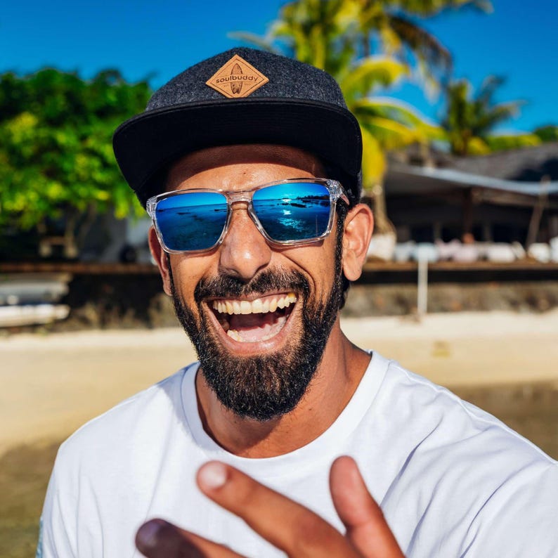Nahaufnahme eines lachenden Mannes mit Sonnenbrille, der die Snapback Cap trägt. Die Freude und der Lifestyle-Charakter der Cap stehen im Fokus.