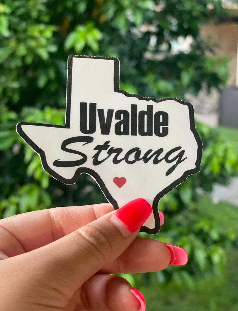 Peut inclure: Un autocollant blanc en forme de l'&eacute;tat du Texas avec les mots "Uvalde Strong" en noir et un petit c&oelig;ur rouge au centre.