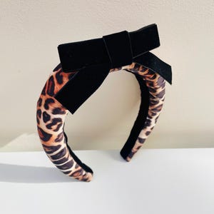 Könnte beinhalten: Ein Stirnband mit einer schwarzen Samtschleife und einem Leopardenmuster.