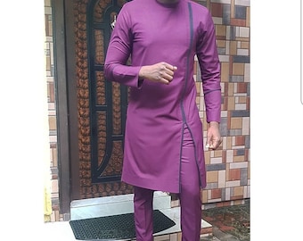 May include: A plum-colored, long-sleeved tunic and matching pants. The tunic has a diagonal black trim and a split front. The outfit is paired with black loafers and a small, dark blue cap. The ensemble is a modern take on traditional attire.