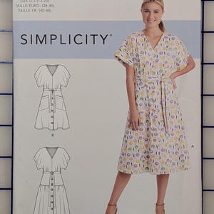 May include: Simplicity sewing pattern S9103. The pattern includes illustrations of a dress with a V-neck, short sleeves, and a button-down front. The dress is shown in a floral print. The pattern size is U.S. 12-20.