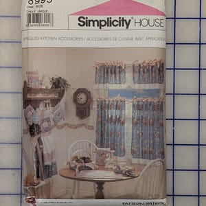May include: Simplicity House pattern 8995 for appliqued kitchen accessories. The envelope features illustrations of blue floral curtains, an apron, oven mitts, and table linens. Text includes the pattern number 8995 and the title Appliqued Kitchen Accessories.