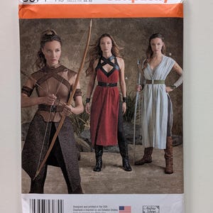 May include: Simplicity sewing pattern featuring three women in fantasy-themed costumes. The pattern cover displays the number 8074, size information, and the Simplicity logo. The costumes include dresses, tops, and pants.