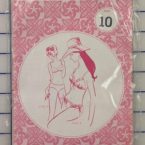 May include: A white ceramic mug with a black handle and the text "But First, Coffee" in a bold, black font. The mug is set against a blurred background, suggesting a cozy setting.