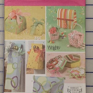 May include: A Simplicity 4320 sewing pattern envelope for various gift boxes and bags. The front displays multiple finished projects including patterned boxes, pouches, and hanging gift bags with ribbons, bows, and tassels. Includes brand logos.