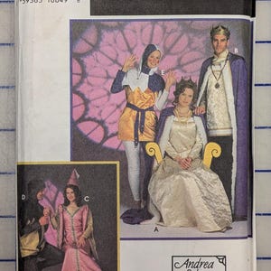 May include: A Simplicity Costumes sewing pattern envelope featuring illustrations of medieval-style garments. The cover displays a jester, a queen in a gold gown, a king in a purple cape, and a princess in a pink dress with the text Andrea Schewe.