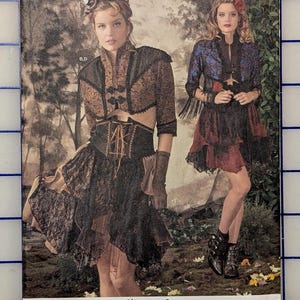 May include: A Simplicity sewing pattern envelope 8409 featuring two outfits with brown and black lace-trimmed jackets, corsets, and skirts. The text includes 8409 H5, SIZE U.S. 6-14, TALLA EURO. 32-40, TAILLE FR. 34-42, and the brand name Simplicity.