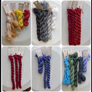 May include: A collection of six panels displaying various bundles of twisted yarn in diverse colors including beige, yellow, red, black, grey, white, blue, green, and purple. Each bundle is attached to a small rectangular paper tag with printed text.