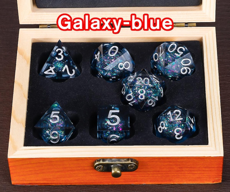 May include: A set of seven galaxy-blue dice with silver numbers in a wooden box. The dice are in a variety of shapes and sizes, including a d4, d6, d8, d10, d%, d12, and d20.
