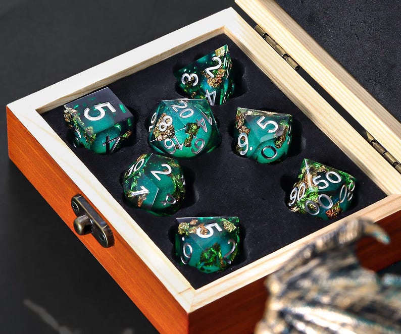 May include: A set of green and gold dice with metallic flecks in a wooden box. The dice are numbered 1 through 6 and have a variety of designs.