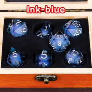 May include: A set of seven blue dice with silver numbers and a glittery finish. The dice are in a wooden box with a brass latch. The box is labelled "Ink-blue".