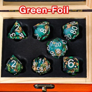 May include: A set of seven green and gold dice with a foil finish. The dice are in a wooden box with a hinged lid. The dice are numbered 1 through 6.