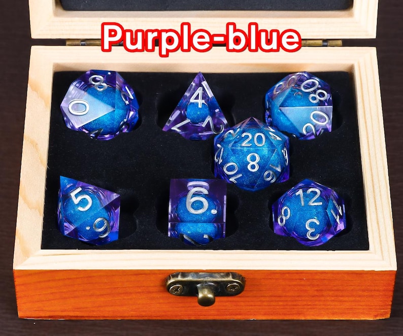 May include: A set of seven purple-blue dice with silver numbers in a wooden box. The dice are in a variety of shapes and sizes, including a d4, d6, d8, d10, d12, and d20.