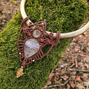 May include: A brown macrame necklace with a gold metal chain and a large, clear quartz crystal pendant. The pendant is surrounded by smaller, clear quartz crystals.