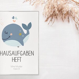 May include: A blue whale with a smiling face and stars on its back, with the text "HAUSAUFGABEN HEFT" and "Mira Muster Klasse 3A" below the whale.
