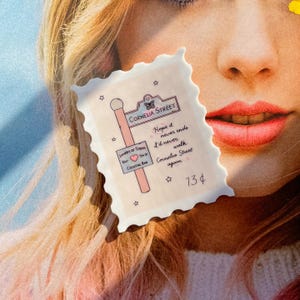 May include: A white sticker with a pink street sign that reads "Cornelia Street". The sticker has a pink butterfly and stars. The text on the sticker reads "Hope it never ends I'd never walk Cornelia Street again". The sticker also has the text "Lovers of Today Eat, Drink,  Your  Cocktail Bar" and "13$".