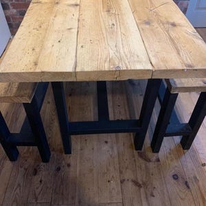 May include: A rustic wooden table with a black metal frame and two matching benches. The table top is made of reclaimed wood with a natural finish.