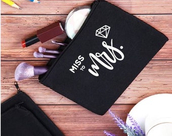 May include: Black canvas makeup bag with a white diamond and the text "Miss to Mrs."