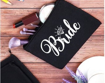 May include: Black zippered makeup bag with a white diamond and the word "Bride" printed on it.