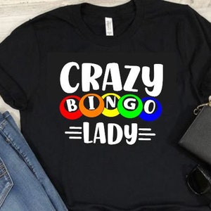 May include: Black t-shirt with white text that reads "Crazy Bingo Lady" with a row of colorful bingo balls.