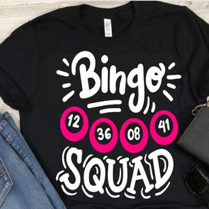 May include: Black t-shirt with white text that says "Bingo Squad" and four pink bingo balls with the numbers 12, 36, 08, and 41.