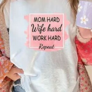 May include: White t-shirt with a pink watercolor background and the text "Mom hard Wife hard Work hard Repeat" in a black square.