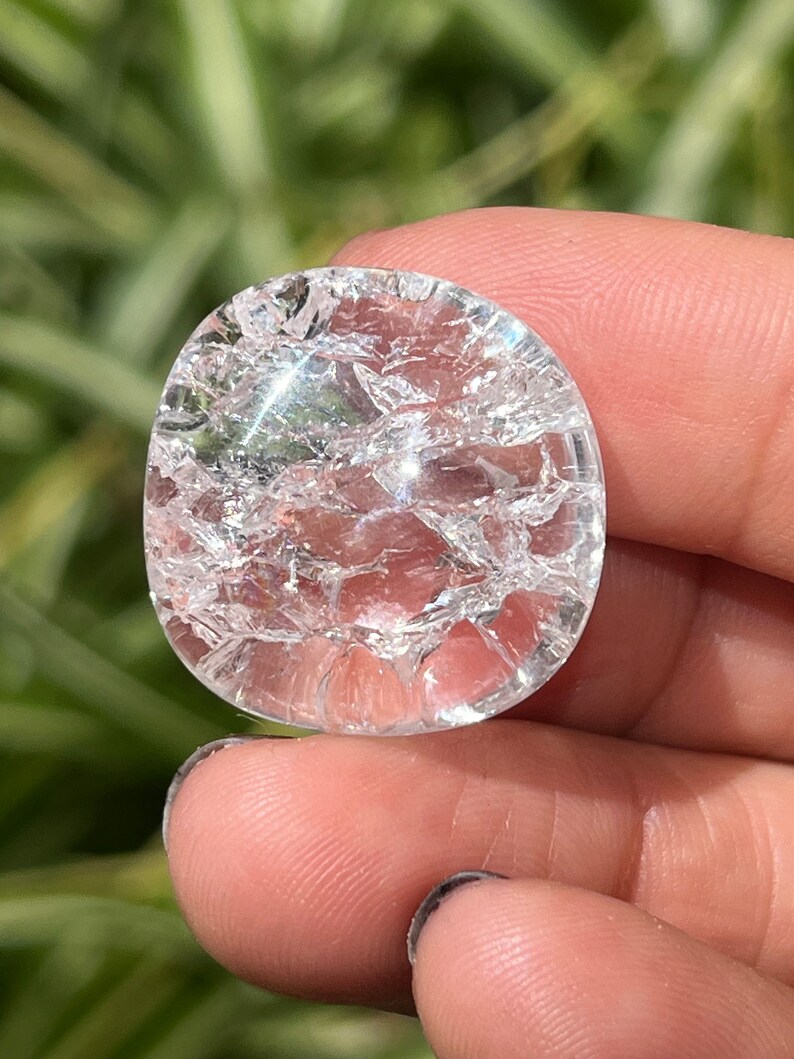 May include: A clear quartz crystal with a cracked surface. The crystal is round and has a smooth, polished finish.