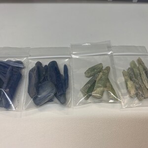 May include: Four small plastic bags containing various types of blue and green crystals. The crystals are in various shapes and sizes.