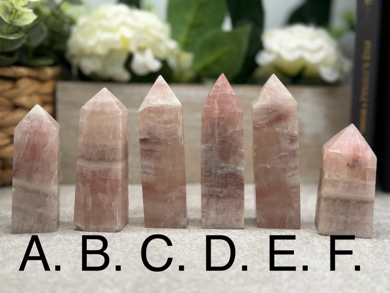May include: Six pink and white striped crystal points, labeled A through F, arranged in a row on a table.