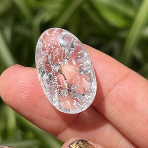 May include: A clear quartz crystal with a unique, cracked texture. The crystal is oval-shaped and has a smooth, polished surface.